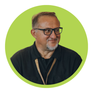 Portrait of a smiling man with glasses and a gray goatee against a lime green circular backdrop