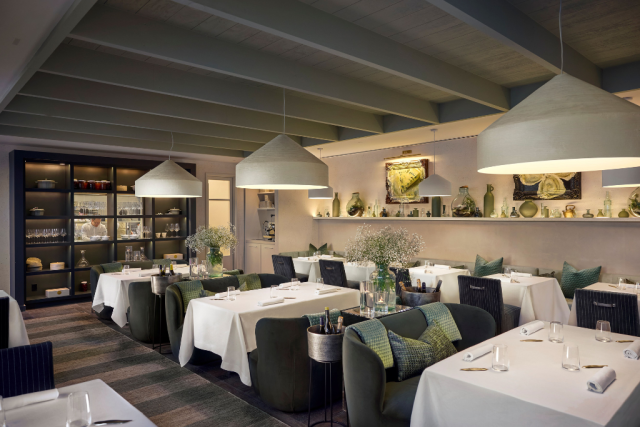 new_zealand Elegant restaurant dining room with white-tablecloth tables, green upholstered chairs, and large pendant lights, creating a warm, upscale ambiance.