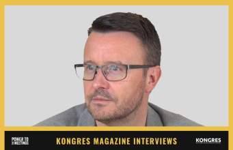 Portrait of a man with short dark hair and glasses, looking to the right; used for Kongres Magazine Interviews feature.