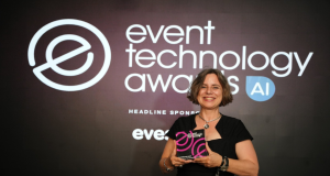 Smiling woman in a black dress on stage holds a pink-and-black award against a dark backdrop that reads 'event technology awards'.
